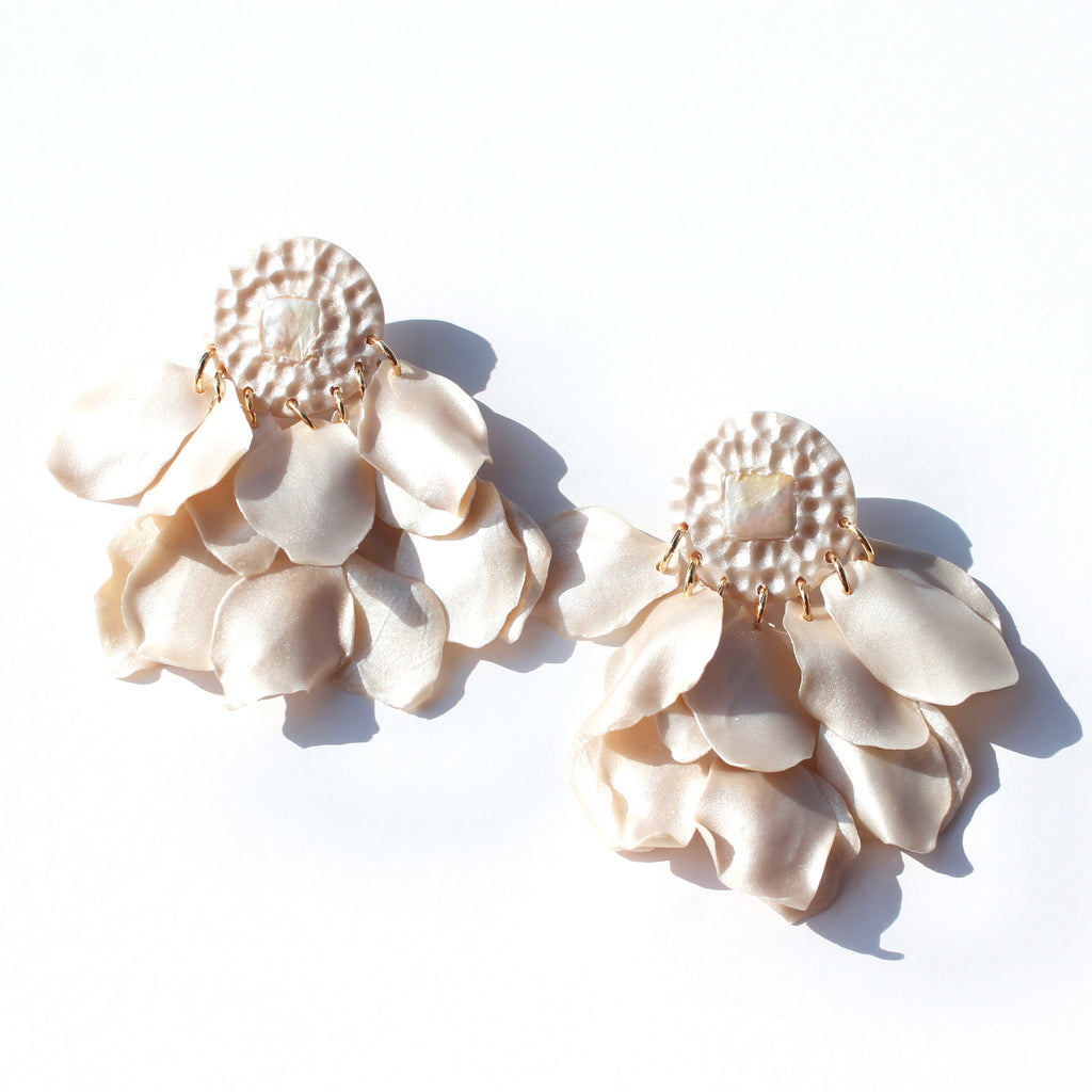 Flower like earrings, petals overflowing with freshwater pearls and hammered texture, laying flat